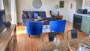 A living room with a sofa, two blue armchairs, a coffee table, a TV, and a kitchen area with a microwave and dishwasher. - Gorgeous and Bright, Lake Marina, Fish, Golf View! (Branson)