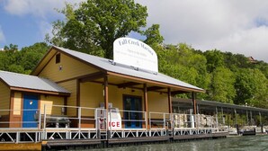 A waterfront building named 'Fall Creek Marina' with a covered deck area, a small boat dock, and a sign indicating it is open to the public. - Gorgeous and Bright, Lake Marina, Fish, Golf View! (Branson)