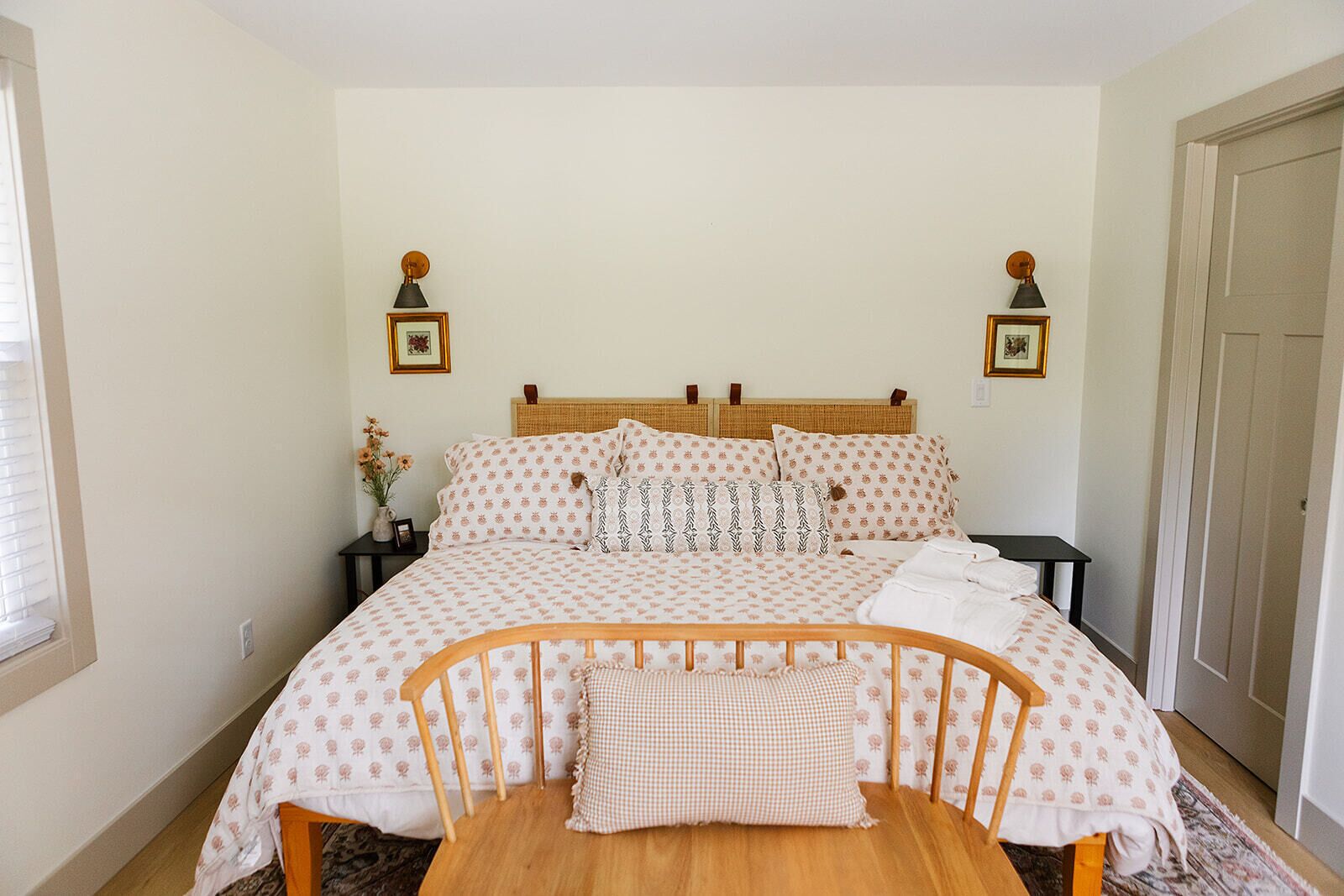 A bedroom with a bed, bedside tables, a nightstand, a chair, and a door.