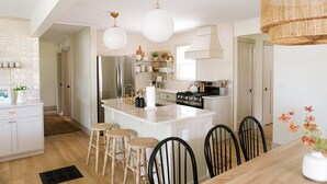 Een moderne keuken met witte kasten, roestvrijstalen apparatuur en een centraal eiland met krukken.