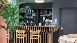 A bar area with a curved counter, two stools, a potted plant, and a surfboard. - B&B HOTEL Versailles Rocquencourt (Le Chesnay-Rocquencourt)