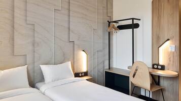 A modern hotel room with two beds, a wooden desk, a chair, and a mirror.