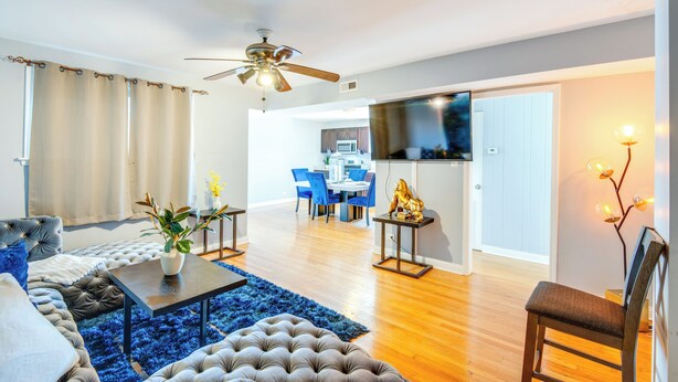 A modern living room with a sofa, coffee table, and a dining area in the background. - Walk to Train & Bus: Updated Chicago Apartment (Chicago)