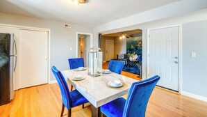 A dining area with a marble table, blue upholstered chairs, and a chandelier. - Walk to Train & Bus: Updated Chicago Apartment (Chicago)