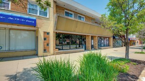 A two-story building with a blue awning, large windows, and a tree in front. - Walk to Train & Bus: Updated Chicago Apartment (Chicago)