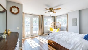 A bedroom with a bed, a ceiling fan, a window with curtains, a wooden dresser, and a wall clock. - Walk to Train & Bus: Updated Chicago Apartment (Chicago)