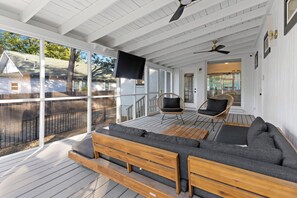A covered porch with a wooden bench and two chairs, a ceiling fan, and a TV mounted on the wall. - 2 Mi to Downtown Austin: Family Home w/ Porch! (Austin)