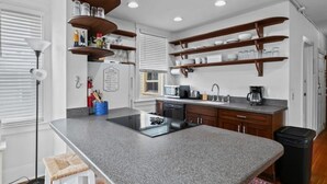 A modern kitchen with granite countertops, wooden shelves, and a central island.