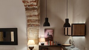 A modern kitchen with a brick wall, wooden cabinets, and pendant lighting. - Suite in the historic center of Naples (Napoli)