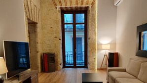 A living room with a wooden floor, a television, a sofa, a coffee table, and a view through a door to an outdoor balcony. - Suite in the historic center of Naples (Napoli)