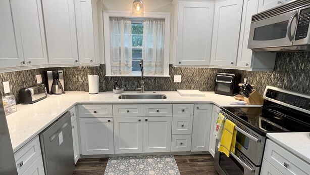 A modern kitchen with white cabinets, a stainless steel sink, a microwave, and an oven. - Family Friendly 3 bedroom close to downtown Raleigh (Raleigh)