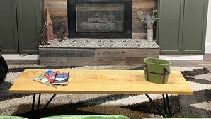 A living room with a fireplace, green sofas, a coffee table with books, and wooden shelves with decorative items. - Family Friendly 3 bedroom close to downtown Raleigh (Raleigh)