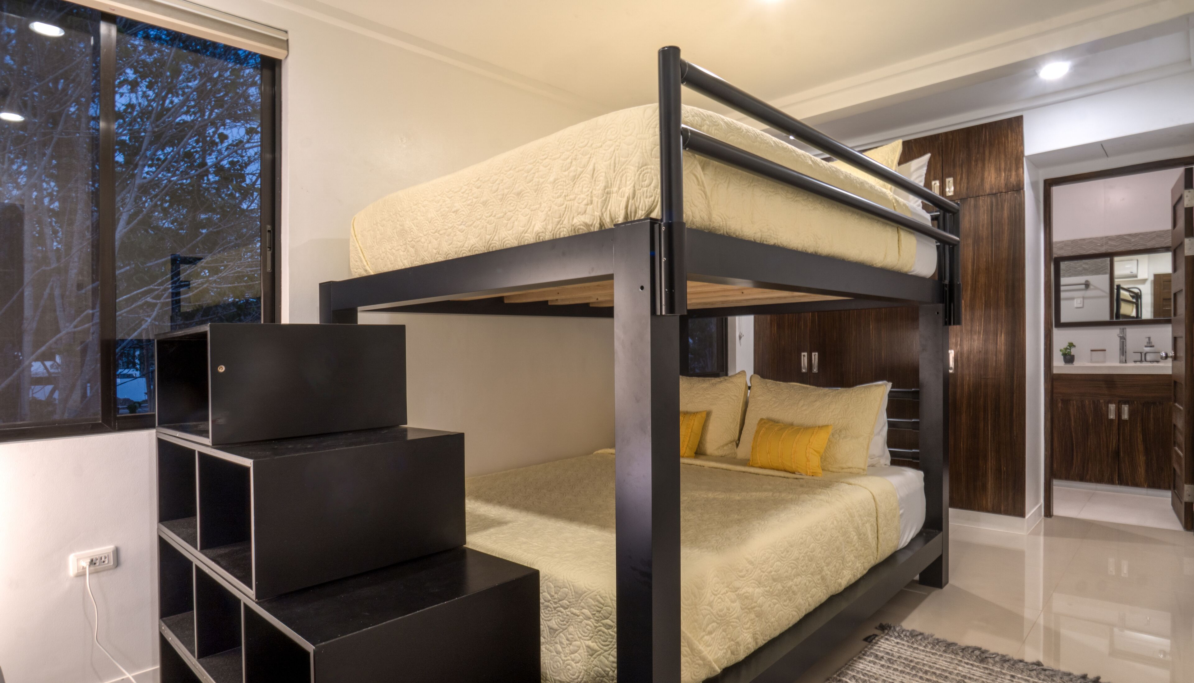 A bunk bed room with a desk and wardrobe.