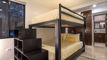 A bunk bed room with a desk and wardrobe.