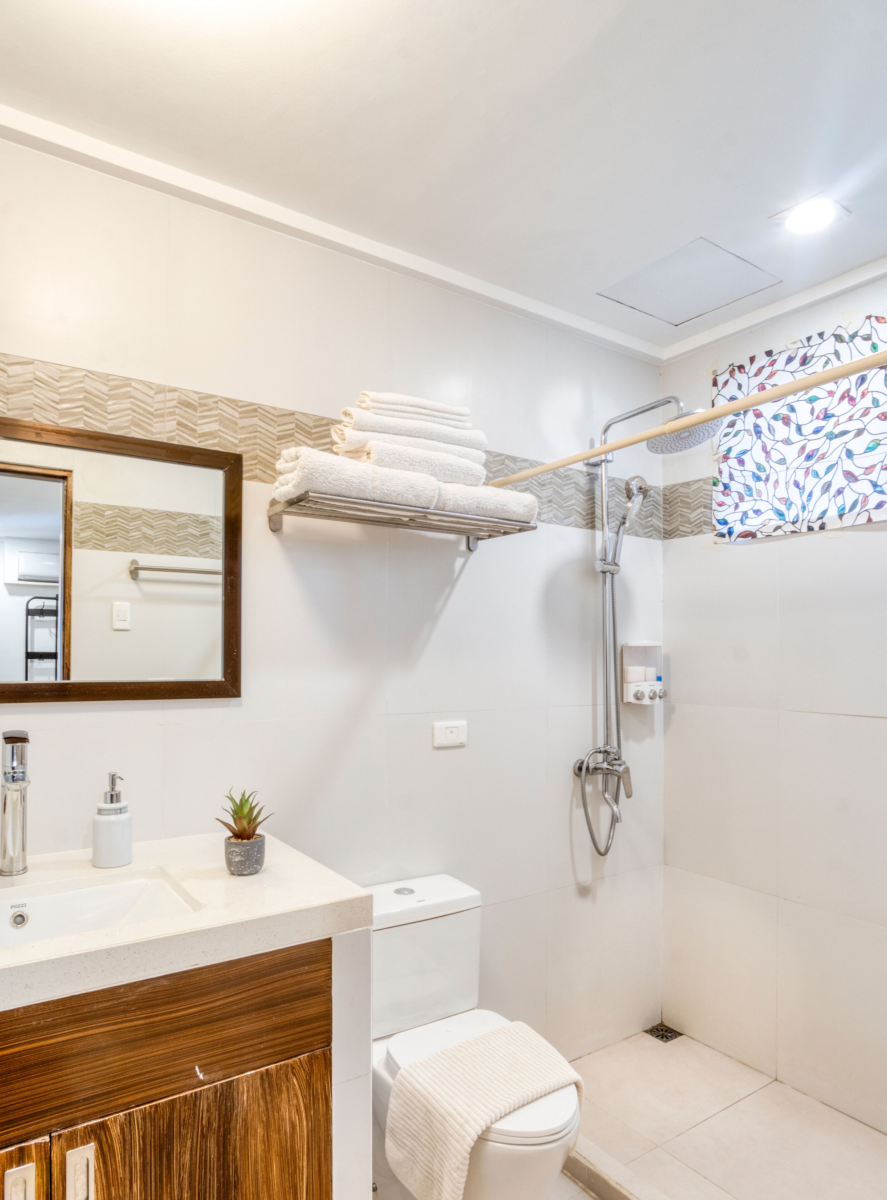 Een moderne badkamer met een wastafel, toilet, douche en handdoekhouder.