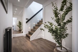 Staircase leads to an upper level, flanked by a potted plant and a radiator.