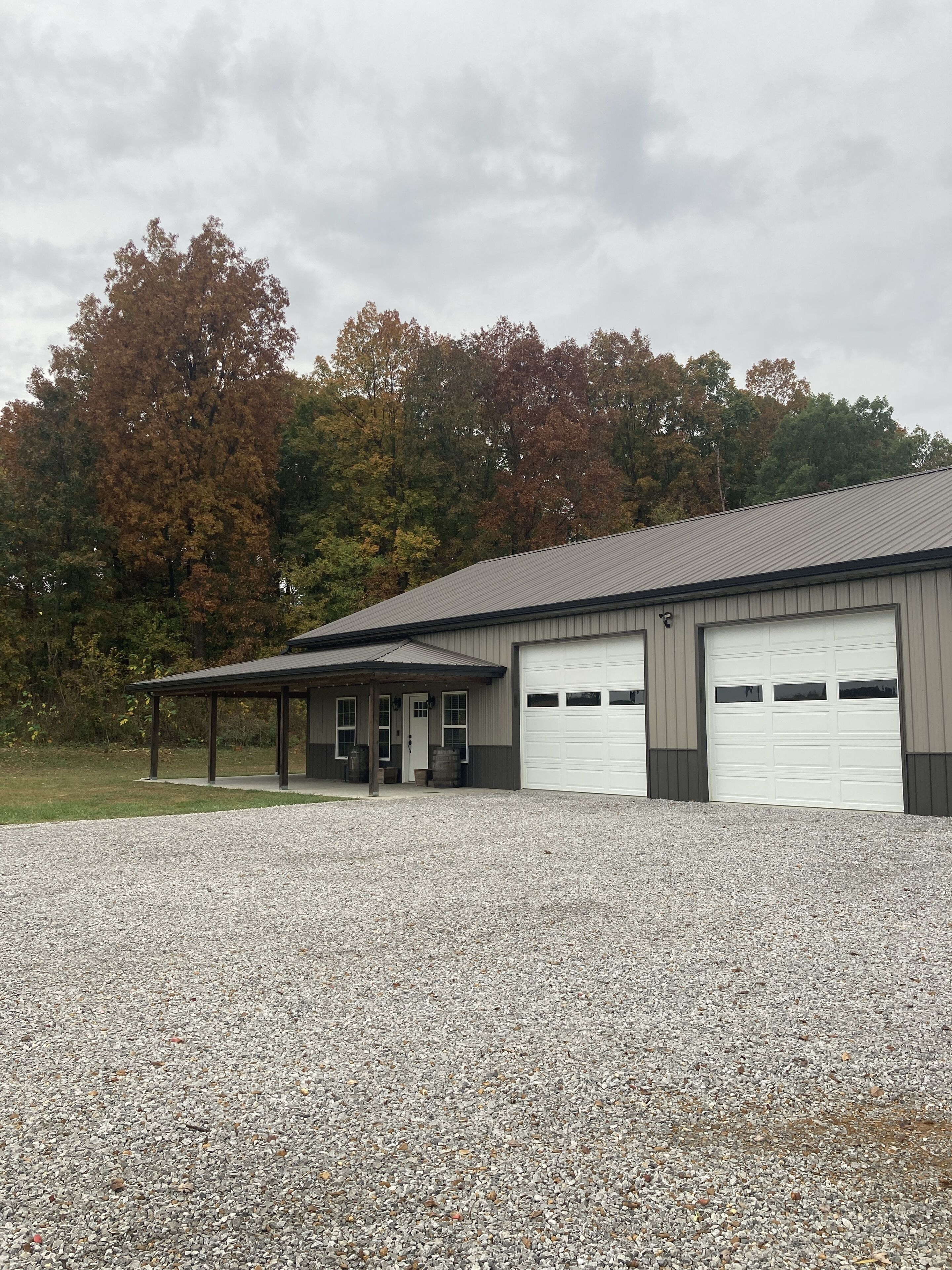 A building with a covered entrance, a gravel driveway, and a garage.