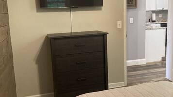 A bedroom with a bed, a dresser, and a TV mounted on the wall.