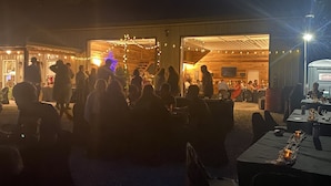 Un espacio para eventos al aire libre con una zona de estar techada y un edificio de paredes abiertas.