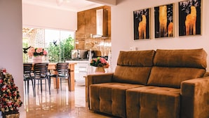 A modern living room with a brown sofa, a dining area with chairs and a table, and a kitchen in the background. - Resort Isla Cancun (Cardoso)