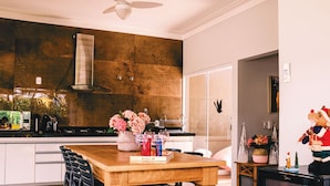 A modern kitchen with a wooden dining table, black chairs, and a built-in stove. - Resort Isla Cancun (Cardoso)