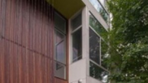 Un edificio moderno de dos pisos con fachada de madera y ventanas amplias.