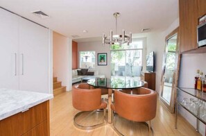 Una cocina moderna con una mesa de comedor de vidrio, dos sillas de cuero y un refrigerador de acero inoxidable.