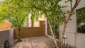 Una terraza de madera con un árbol pequeño y un muro de ladrillo.