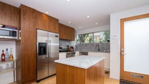 Una cocina moderna con armarios de madera, electrodomésticos de acero inoxidable y una isla de mármol.