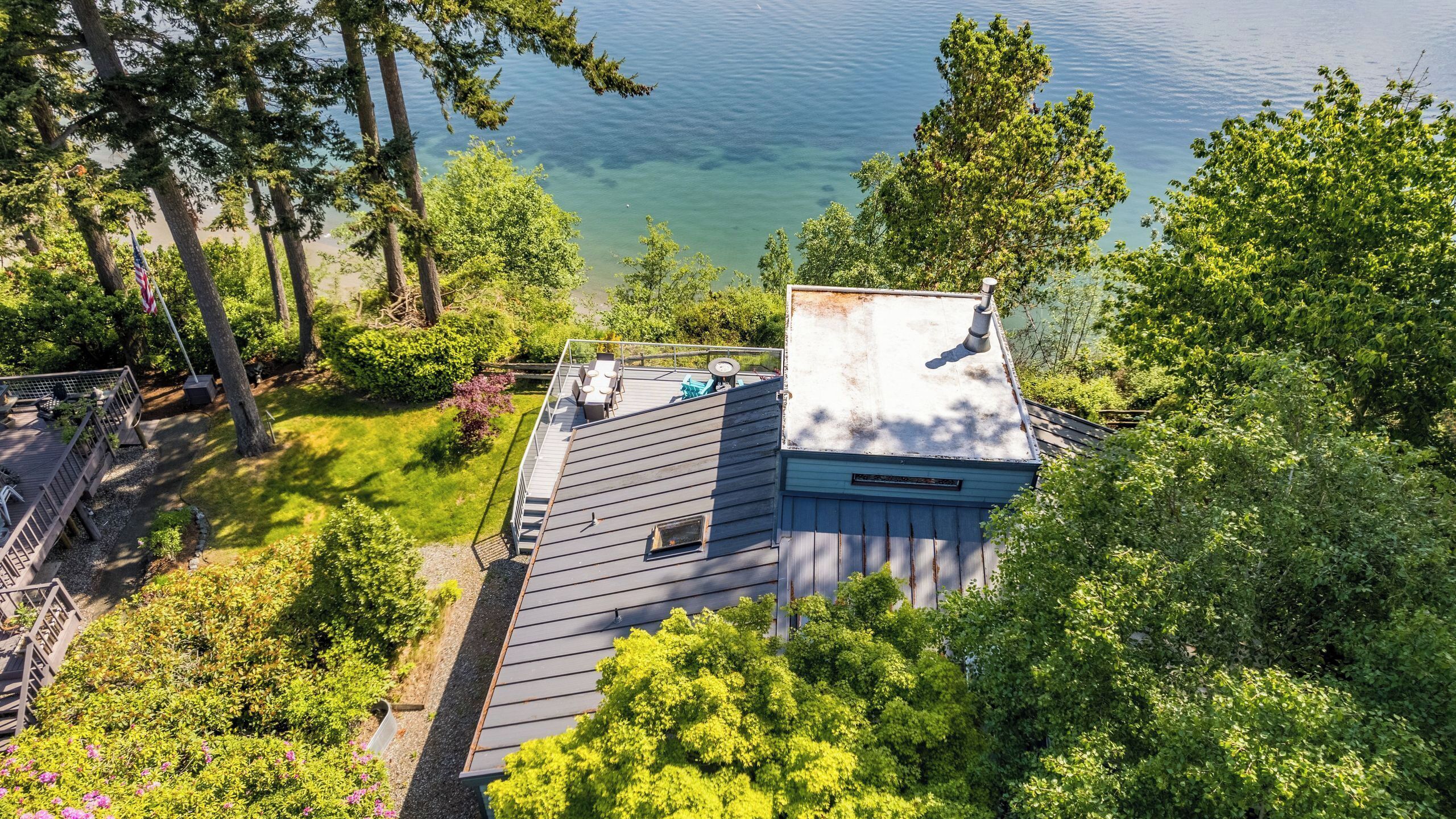 A house with a deck, a small shed, and a view of a lake.