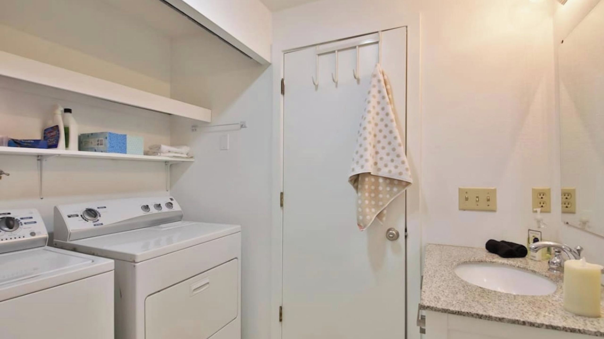 A laundry area with a washing machine, dryer, and a door with a towel hanging on a hook.