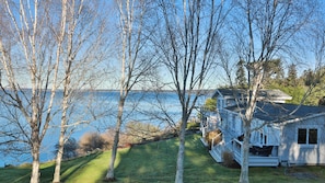 Ein Haus mit Veranda, Rasen und Blick auf das Wasser.