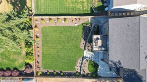 A residential property with a large lawn, a patio area with seating, and a house with a sloped roof. - Twin Oaks Retreat by Avantstay Mins to Freeland (Freeland)