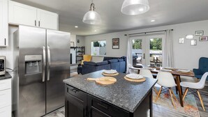 A modern kitchen with a stainless steel refrigerator, granite countertops, and pendant lighting. - Twin Oaks Retreat by Avantstay Mins to Freeland (Freeland)