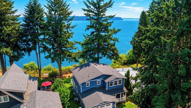 En bostadsfastighet med ett tvåvåningshus, ett synligt garage och en trädgård med ett rött parasoll.