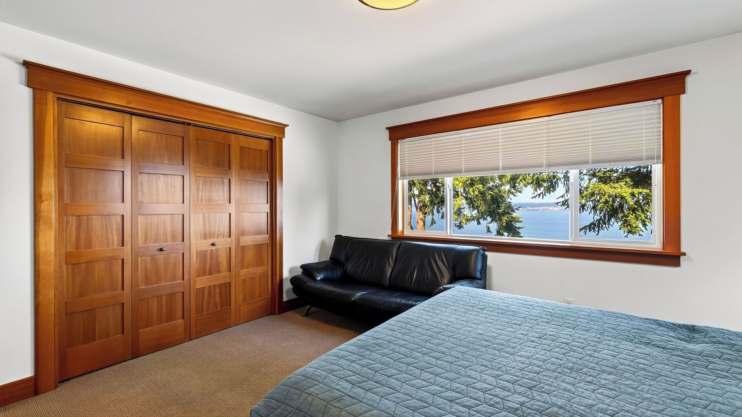 A bedroom with a large closet, a window with a view, and a bed.