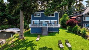 A two-story house with a balcony, a lawn with two sun loungers, and a large tree in the foreground. - Cascade View Haven by Avantstay Saratoga Vistas (Langley)