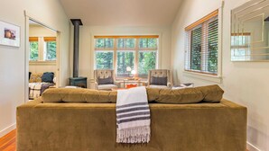 A cozy living room with a sofa, two armchairs, a fireplace, and large windows with blinds. - The Cottage at Herons Roost by Avantstay (Langley)
