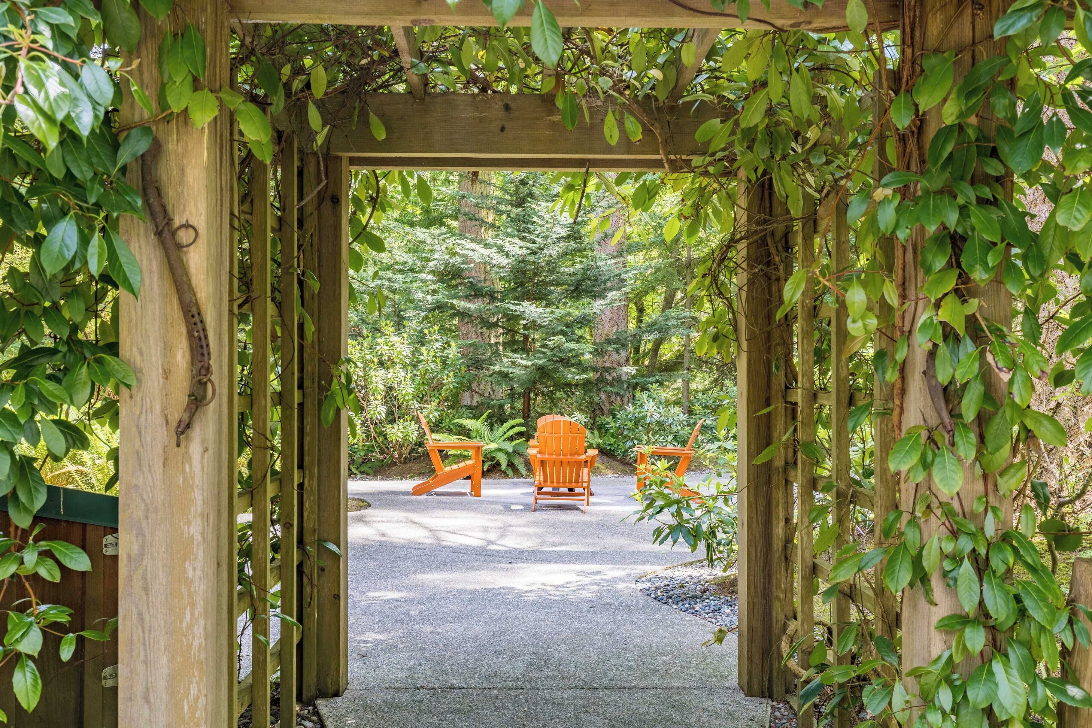 Una pérgola de madera con un camino que conduce a un área de estar al aire libre.