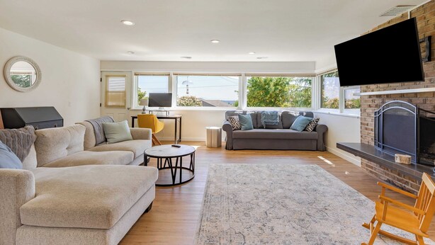 A modern living room with a fireplace, sofas, a coffee table, and a TV. - Sunny Side Island Retreat by Avantstay Backyard (Freeland)