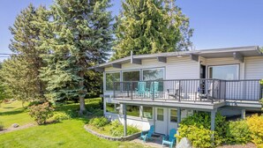A two-story house with a balcony, surrounded by a well-maintained garden and tall trees. - Sunny Side Island Retreat by Avantstay Backyard (Freeland)