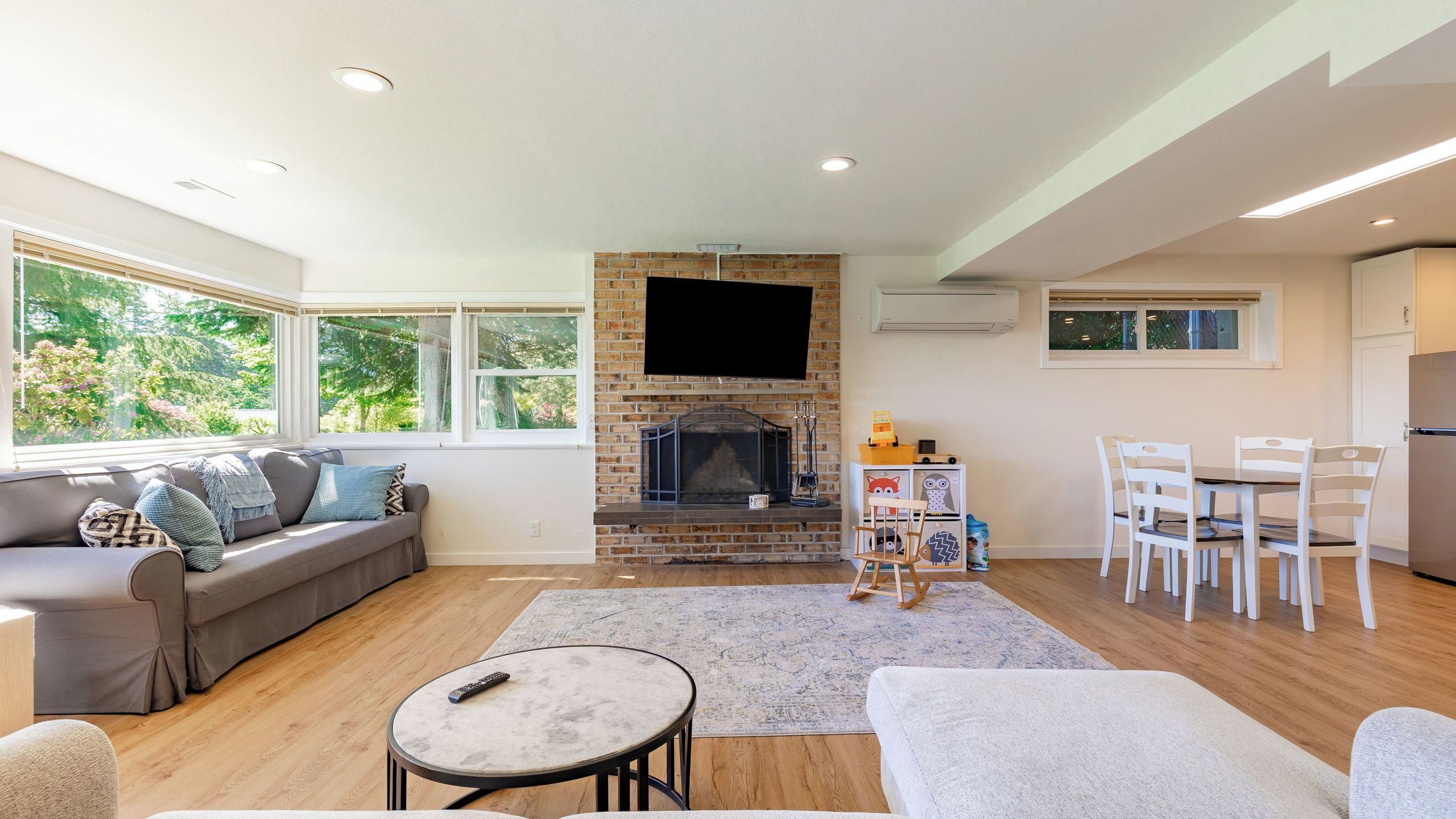 A living room with a fireplace, sofa, TV, and dining area.