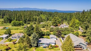 A residential area with houses surrounded by dense forests and a clear view of mountains in the distance. - Sunny Side Island Retreat by Avantstay Backyard (Freeland)
