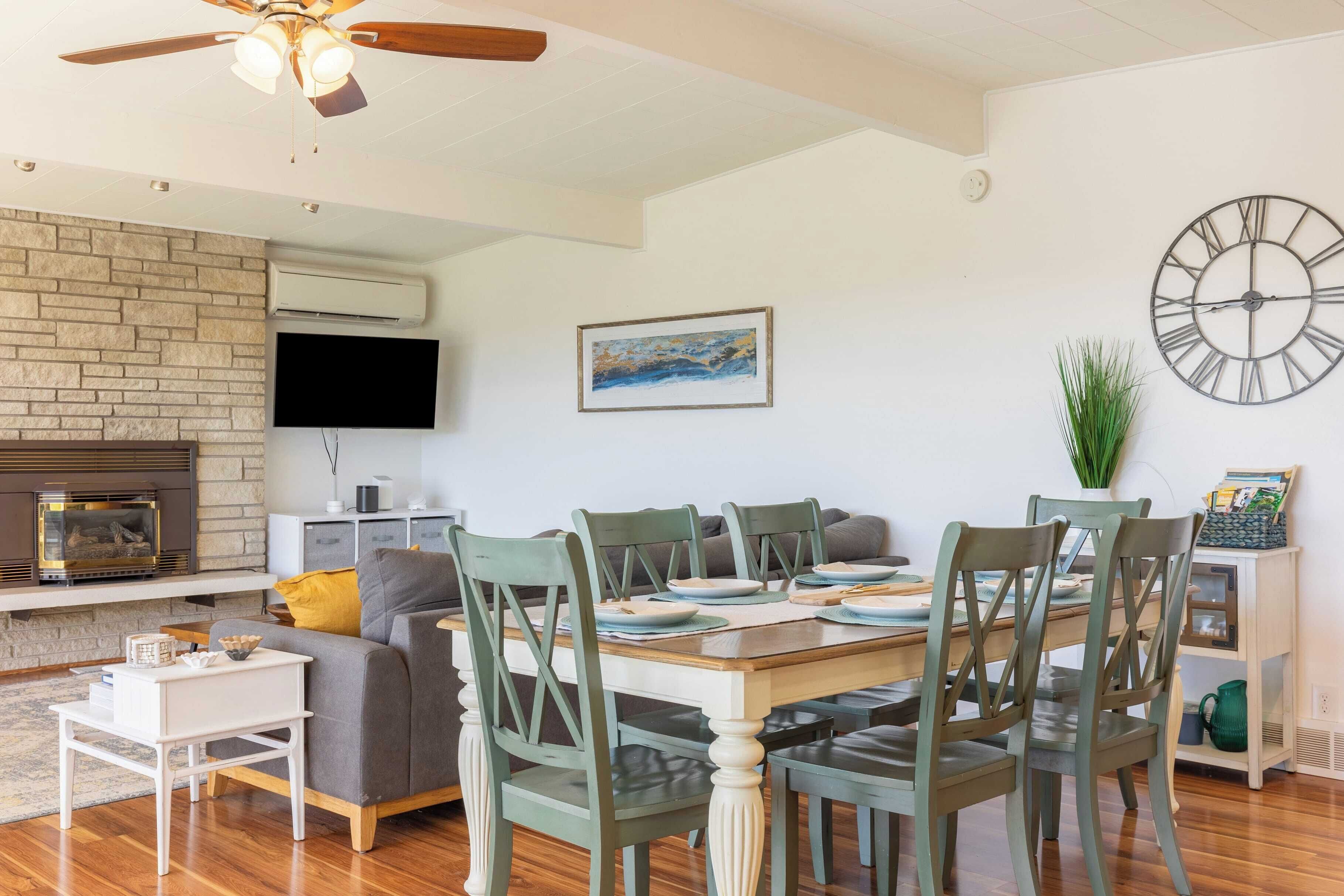 A dining area with a wooden table, green chairs, and a modern fireplace.