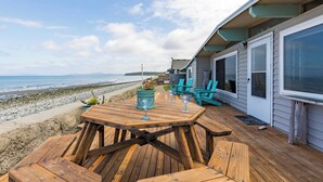 Una terraza de madera con una mesa y sillas que da a la playa.
