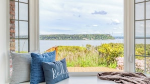 A view from a window with a bench, pillows, and a blanket. - Colonial Bluff House Above the Sea by Avantstay (Langley)