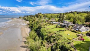 A coastal residential area with houses, a beach, and a forested hillside. - Colonial Bluff House Above the Sea by Avantstay (Langley)