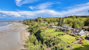 Una zona residencial costera con casas, una playa y una ladera cubierta de bosque.