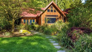 A wooden cabin with a red roof, surrounded by lush greenery and a stone pathway. - Rhythm Waters by Avantstay Garden Paradise, Pond (Langley)