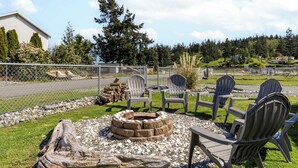 A backyard with a fire pit, Adirondack chairs, and a wooden deck. - Sunny by the Sound by Avantstay Coastal Escape (Coupeville)